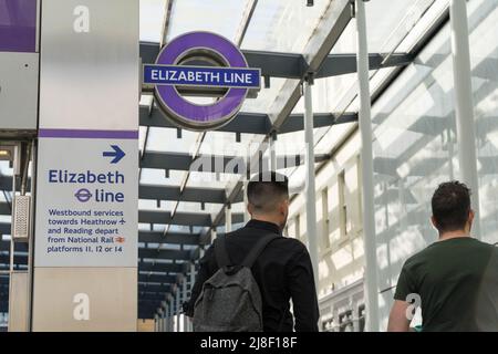 Zwei Passagiere gehen an einem Elizabeth LINE-Logo, der neuen crossrail-Bahnlinie (violette Linie), Paddington Station London England vorbei Stockfoto