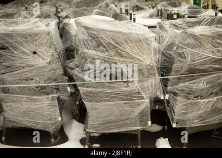 Stühle in Film. Vorbereitung für den Transport der Möbel. Lager von Tischen und Stühlen auf der Straße. Stockfoto