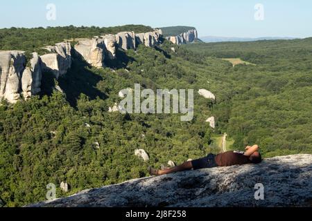 Im Sommer geht ein Mann durch eine Höhlenstadt. Touristen beobachten die Felsen. Darauf ruhen. Die touristische Route in der Krim. Die Krimberge im Reisemeer Stockfoto