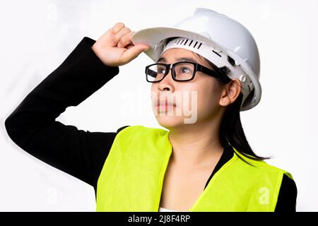 Selbstbewusste Ingenieurin mit Helm und Blick in die Ferne isoliert auf weißem Hintergrund im Studio. Stockfoto