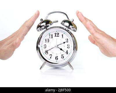 Retro-Wecker, der in der Mitte einer weiblichen Hand platziert ist und eine Stoppgeste auf weißem Hintergrund macht. Stockfoto