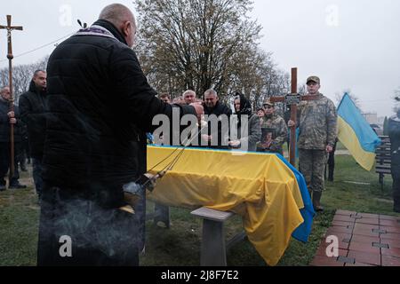 Lviv, Ukraine. 22. April 2022. Während der Beerdigung des 43-jährigen Junior-Sergeanten Andrij Iwanowitsch Tsyrba, der in der Ostukraine vom russischen Militär getötet wurde, führt ein Priester eine Zeremonie auf dem Ryasne-Friedhof durch. (Bild: © Joe M O'Brien/SOPA Images via ZUMA Press Wire) Stockfoto