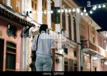 Reisende mit Maske zu Fuß auf der Straße Phuket Altstadt mit Gebäude sino portugiesischen Architektur in Phuket Altstadt Phuket, Thailand. Reisekonz Stockfoto