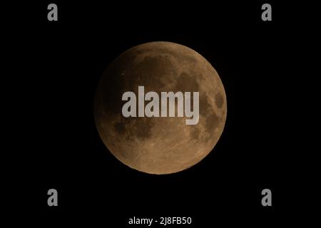 London, Großbritannien. 16. Mai 2022. UK Wetter: Super Blood Moon - partielle Finsternis um 03:21 Uhr. Ein dramatischer Superblutmond tritt in die frühen Stadien einer totalen Mondfinsternis ein, wobei ein schwacher Schatten von oben links abdunkelt, wie er von Südosten Londons aus gesehen wird. Der Mond erscheint rot, wenn er in den Schatten der Erde fällt. Der Effekt wird durch die Erdatmosphäre verursacht, die etwas vom Sonnenlicht auf sie zubiegt. Die einzige vollständige Mondfinsternis dieses Jahres findet während eines Supermondes statt, wenn sich der Mond in seiner Umlaufbahn am nächsten zur Erde befindet, was ihn größer erscheinen lässt. Bild: Guy Corbishley/Alamy Live Stockfoto
