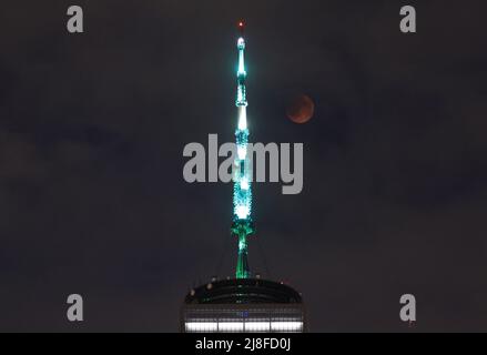 New York, Usa. 16.. Mai 2022. Am Sonntag, den 15. Mai 2022, zieht eine seltene totale Mondfinsternis des „Super Flower Blood Moon“ an der Spitze des One World Trade Center und der Manhattan Skyline in New York City vorbei. Foto von John Angelillo/UPI Credit: UPI/Alamy Live News Stockfoto