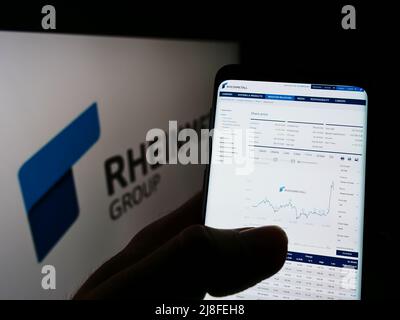Person, die Mobiltelefon mit Website der Rheinmetall AG auf dem Bildschirm vor dem Logo hält. Konzentrieren Sie sich auf die Mitte des Telefondisplays. Stockfoto