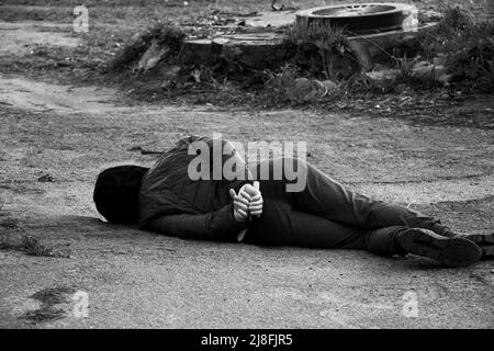 Eine tote Ukrainerin liegt auf der Straße mit ihren Händen an einem weißen Seil gebunden und wurde in der Ukraine, einem Todesprotest in der Stadt, im Rücken getötet Stockfoto