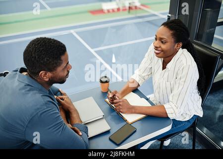 Porträt einer lächelnden schwarzen Frau, die während des Treffens den Sportler im Trainingszentrum interviewte Stockfoto