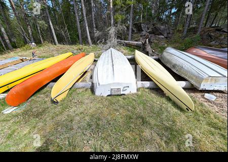 Boote Kajaks und Kanus liegen auf Baumstämmen Stockfoto