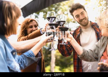 Fröhliche Freunde, die Spaß haben, Rotwein im Weinberg zu trinken - Milenial Menschen toasting zusammen auf dem Land Bauernhaus - Multi-Generationen-Freundschaft Stockfoto