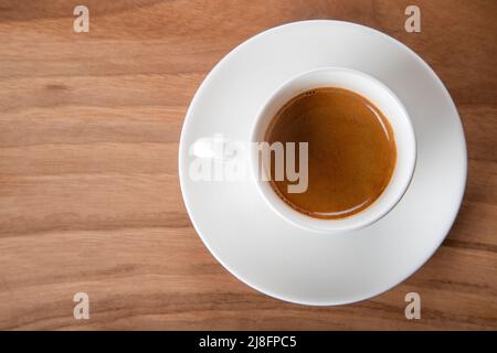 Weiße Tasse Espresso auf Holzhintergrund, Draufsicht Stockfoto