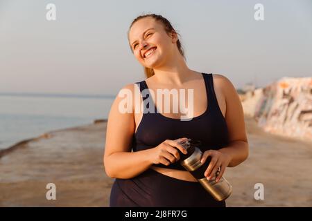 Ingwer junge Frau Trinkwasser während Yoga üben im Freien Stockfoto