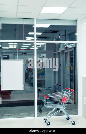 Einzeleinkaufswagen in der Eingangshalle des Supermarkts mit leerem Banner Stockfoto