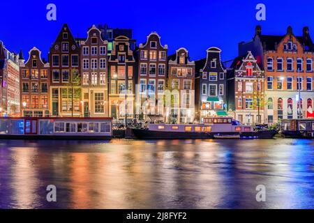 Amsterdam, Niederlande. Farbenfrohe Tanzhäuser am Damrak-Kanal. Stockfoto