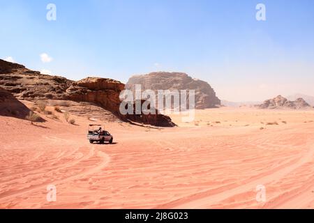 Jeep-Safari in der Wüste Wadi Rum, Jordanien. Touristen im Auto fahren im Gelände auf Sand zwischen den schönen Felsen. Wüstenlandschaft mit rotem Sand und felsigen m Stockfoto