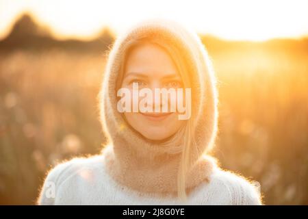 Portrait of Young Pretty Caucasian Happy Girl Woman in Woolen Jacket Bluse und Brown gestrickte Haube posiert im frühen Frühlingswald in Sunny Day. Viel Spaß Stockfoto