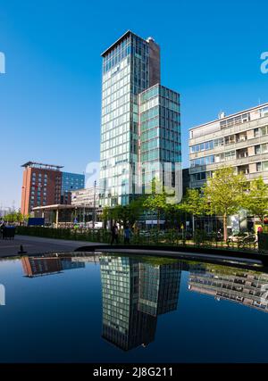 Freiburg im Breisgau, Deutschland - 13. April 2022: Wohngebäude, Büros, Hotels und Wolkenkratzer mit ihren Spiegelungen im Dach eines dunklen Autos Stockfoto