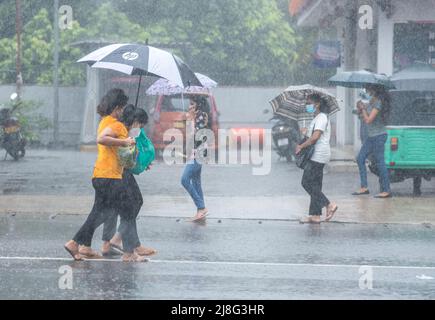 Colombo, Sri Lanka. 14.. Mai 2022. Menschen gehen während eines starken Regenschauens in Colombo Sri Lanka am 14. Mai 2022 durch die Straße. (Bild: © Vimukti Embldeniya/Pacific Press via ZUMA Press Wire) Stockfoto