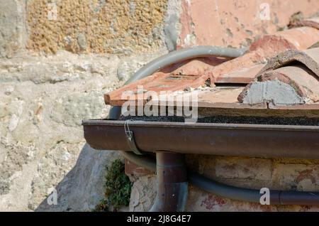 Haus: Gebäude mit Dachschräge mit Ziegelsteinen, Dachrinne aus freiliegendem Blech. Die Schindeln sind aus Lehm, mit einer selbstsichernden Form. Stockfoto