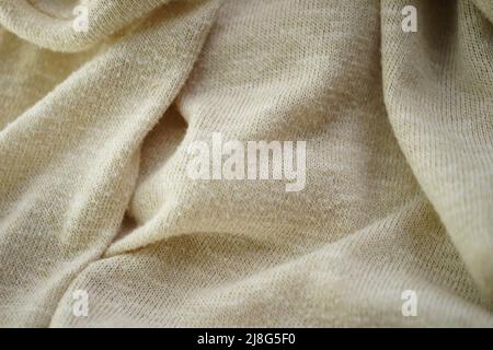 Hintergrund aus mattem, cremefarbenem weichem Stoff. Cremig gestricktes Stoffmuster. Stockfoto