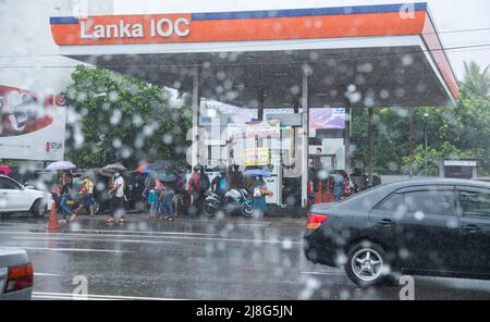 Colombo, Sri Lanka. 14.. Mai 2022. Menschen warten an der Tankstelle während eines starken Regenschauens in Colombo Sri Lanka am 14. Mai 2022. (Bild: © Vimukti Embldeniya/Pacific Press via ZUMA Press Wire) Stockfoto