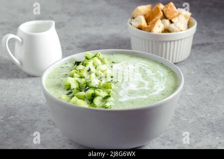 Gurke Gazpacho. Grüne frische kalte Sommersuppe auf grauem Hintergrund. Konzept der veganen Küche Stockfoto