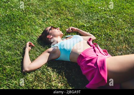 Im Gras liegen und im Sommer träumen. Frau fühlt sich gut, Optimismus. Gesund herrlich hübsches Modell entspannend. Sorglose Stimmung. Friedliche Erholung. Stockfoto
