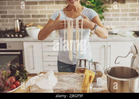 Der Prozess des Kochens von Nudeln mit einem Teigmixer und Nudelschneider in der heimischen Küche Stockfoto