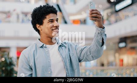 Portrait afroamerikanischer Mann Kerl Student männlich drinnen mit Handy App Telefon winken hallo reden Videoanruf Konferenz Chat Freunde Remote Stockfoto