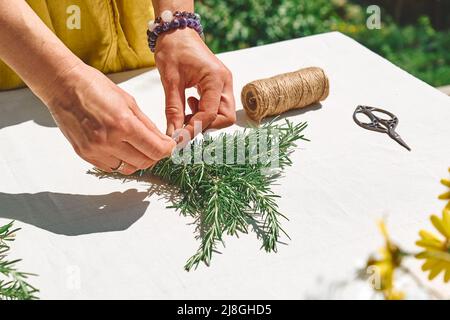 Alternative Medizin. Sammlung und Trocknung von Kräutern. Frau hält in ihren Händen einen Bund Rosmarin. Kräuterkundige Frau bereitet frisch duftenden Bio Stockfoto