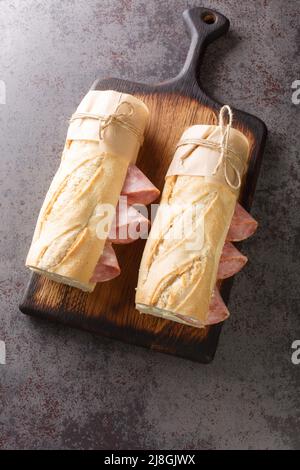 Klassisches Pariser Jambon-Beurre-Sandwich aus der Nähe auf dem Holzbrett. Vertikale Draufsicht von oben Stockfoto