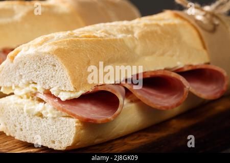 Französisches Sandwich knuspriges Baguette, leicht gesalzene Butter und dünn geschnittener Schinken, idealerweise Jambon de Paris in der Nähe auf dem Holzbrett. Horizontal Stockfoto