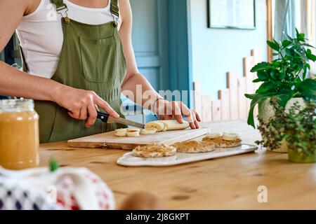 Eine Frau, die ein gesundes Frühstück oder Brunch macht und Erdnussbutter auf einem gepufften Maiskuchen verteilt. Protein-Diät gesunde Ernährung Konzept. Stockfoto