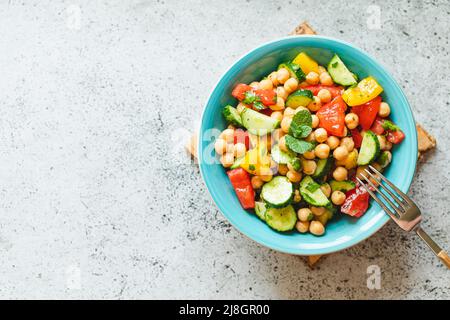 Kichererbensalat mit Tomaten, Gurke, Petersilie, Zwiebeln auf einem Teller, selektiver Fokus. Gesunde vegetarische Küche, orientalische und mediterrane Küche. Chic Stockfoto