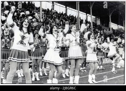 Verdreher und Cheerleader der Lincoln High School reagieren auf einen Touchdown in einem Spiel gegen Midwood High auf dem Midwood Field in Brooklyn, New York, um 1980. Stockfoto