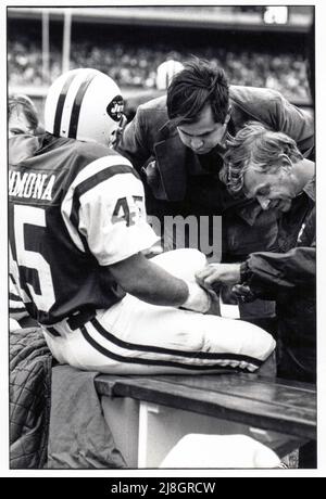 Dr. Robert Grossman, Orthopäde der New Yorker Jets, und Jeff Snedyker, langjähriger Trainer, kleben das Handgelenk des zurücklaufenden Lou Giammona am Rande eines Fußballspiels im Shea Stadium in New York City aus dem Jahr 1976 auf. Stockfoto