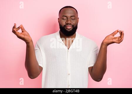 Foto von verträumten lustigen jungen Mann tragen weißes Hemd lächelnd genießen Yoga isoliert rosa Farbe Hintergrund Stockfoto