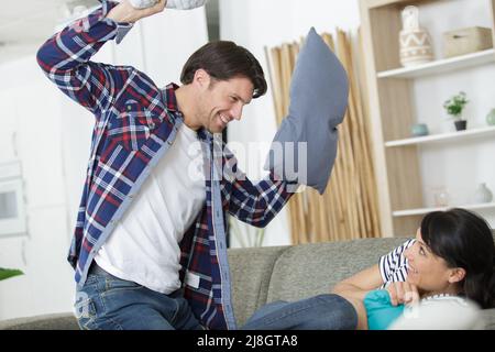 Verspieltes Paar, das einen Kissenkampf führt Stockfoto