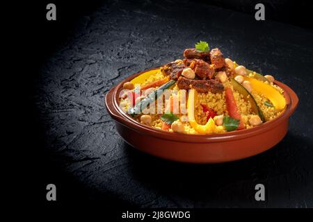 Fleisch- und Gemüsecouscous, festliche afrikanische Küche, auf dunklem Hintergrund mit Platz für Text Stockfoto