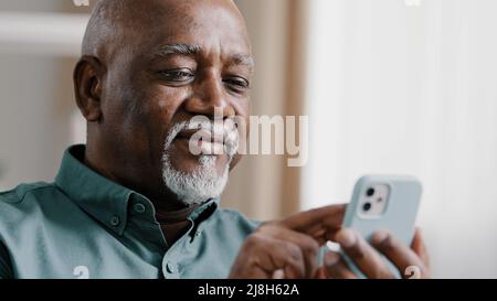 Ältere ältere alte afrikanische 60s biracial Mann mit Telefon amerikanischen Geschäftsmann männlichen Großvater kostenlose wi-Fi Chat mobile App zu Hause Surfen im Netz Stockfoto