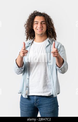 Nahaufnahme eines jungen gut aussehenden Mannes mit langen und lockigen Haaren zeigt mit seinem Finger, isoliert auf weißem Hintergrund. Hochwertige Fotos Stockfoto