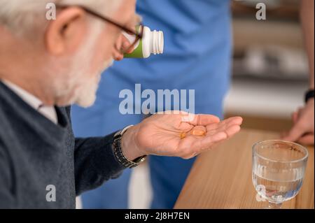 Alter Mann, der Medikamente von einer Hauskrankenschwester erhält Stockfoto