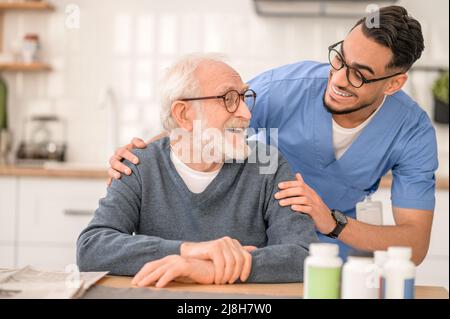 Fürsorglicher Mitarbeiter im Gesundheitswesen, der eine ältere Person umarmt Stockfoto