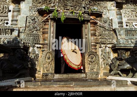 Belur, Karnataka, Indien: Ein großer zeremonieller Sonnenschirm wird innerhalb des Chennakeshava Tempels des 12.. Jahrhunderts getragen.