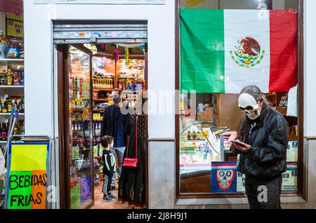 Granada, Andalusien, Spanien : am Tag der Toten steht ein mexikanischer Mann mit Totenkopfmaske vor einem mexikanischen Lebensmittelgeschäft. Stockfoto