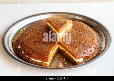 Brot Kadayif auf weißem Hintergrund. Geschnittenes Brot kadayif in einem Tablett. Lokaler Name ekmek kadayif Stockfoto