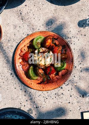 Burrata-Käse mit Tomaten. Salat in Sommersonnenlicht. Stockfoto
