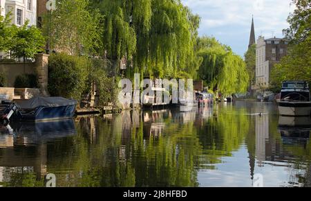 Blick auf den Regent-Kanal und die Rückseite des Houses of St Marks Crescent mit festgetäutem Kanal schmale Boote mit St. Marks-Kirche im Hintergrund, London U Stockfoto