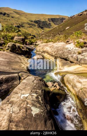 Ein Gebirgsbach, der eine tiefe Furche in den glatten, verwitterten Sandsteinausbiss im Injisuthi-Abschnitt der Drakensberg Mountains geschnitten hat Stockfoto