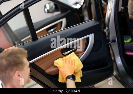 Der Mann putzt den Türgriff des Autos mit Stoff und Auto-Details Stockfoto